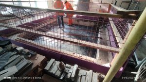 Steel reinforcement installation in prepared formwork for concrete structure, with site operatives in PPE on suspended platform