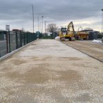 Permeable car park sub-base and retaining wall preparation at OCO Technology site in Leeds, showing compacted stone surface and precast concrete retaining walls.