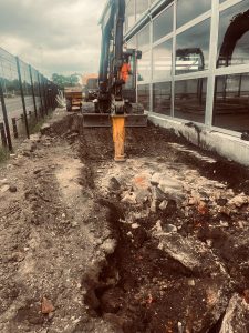 Excavator carrying out drainage excavation alongside the West Stand at Elland Road Stadium, Leeds
