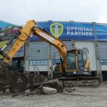 Excavator carrying out excavation works outside the West Stand at Elland Road Stadium, Leeds