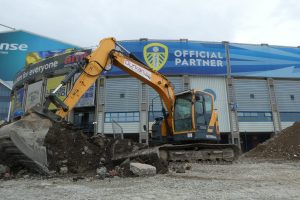 Excavator carrying out excavation works outside the West Stand at Elland Road Stadium, Leeds